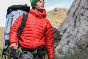 مردی در کوهستان برفی که کاپشن پر قرمز پوشیده